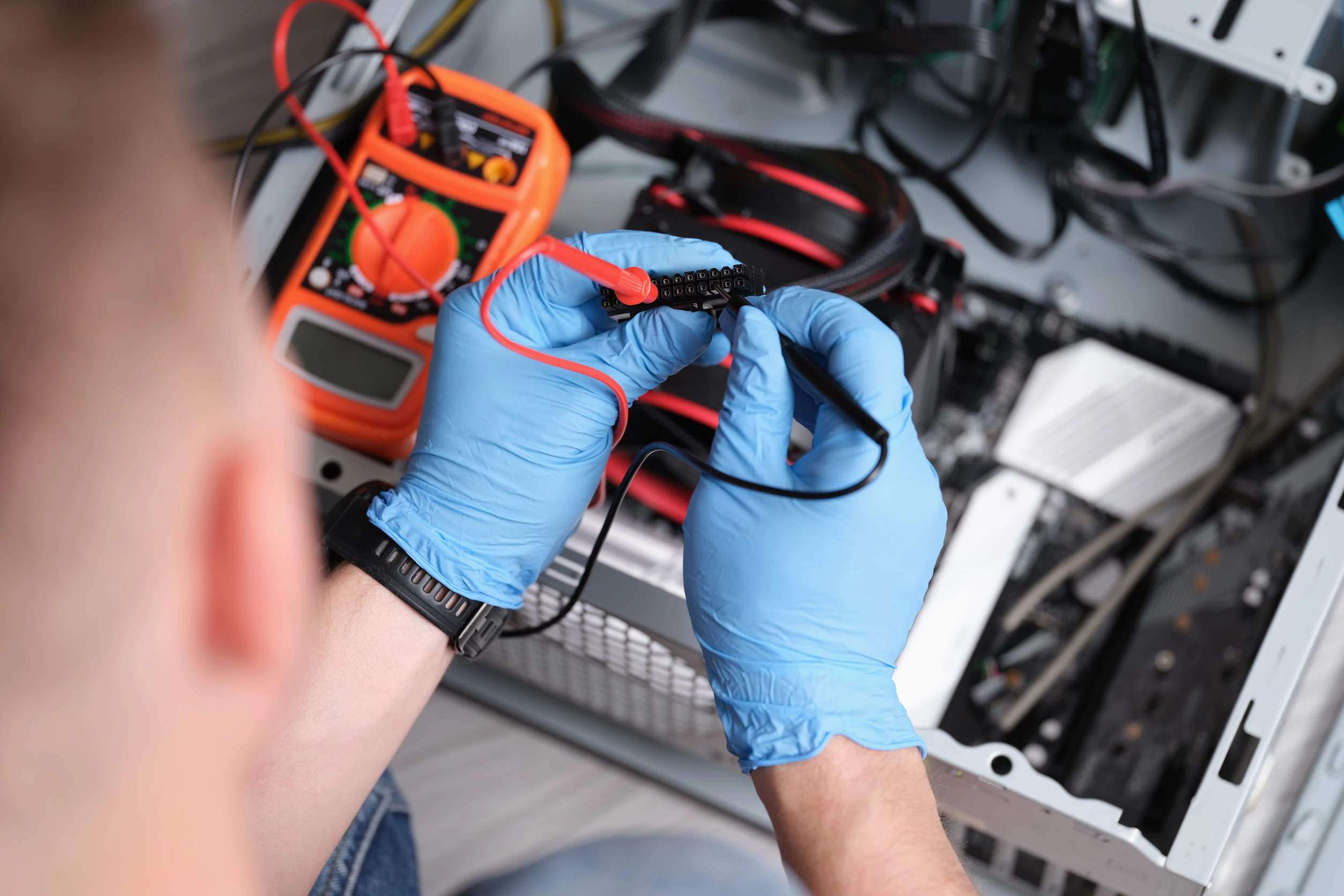 Techniker misst PC-Netzteilstecker mit Multimeter bei Computer-Reparatur