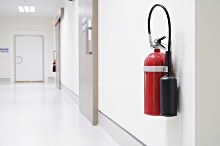 Roter Feuerlöscher im weißen Flur eines Gebäudes, Brandschutz Sicherheit